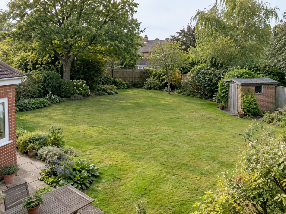 A spacious garden with lawn, hedges and mature trees